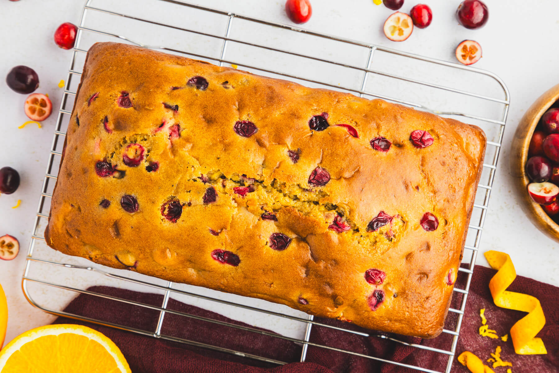 A golden baked whole Orange Cranberry Loaf cooling on a wire rack. 