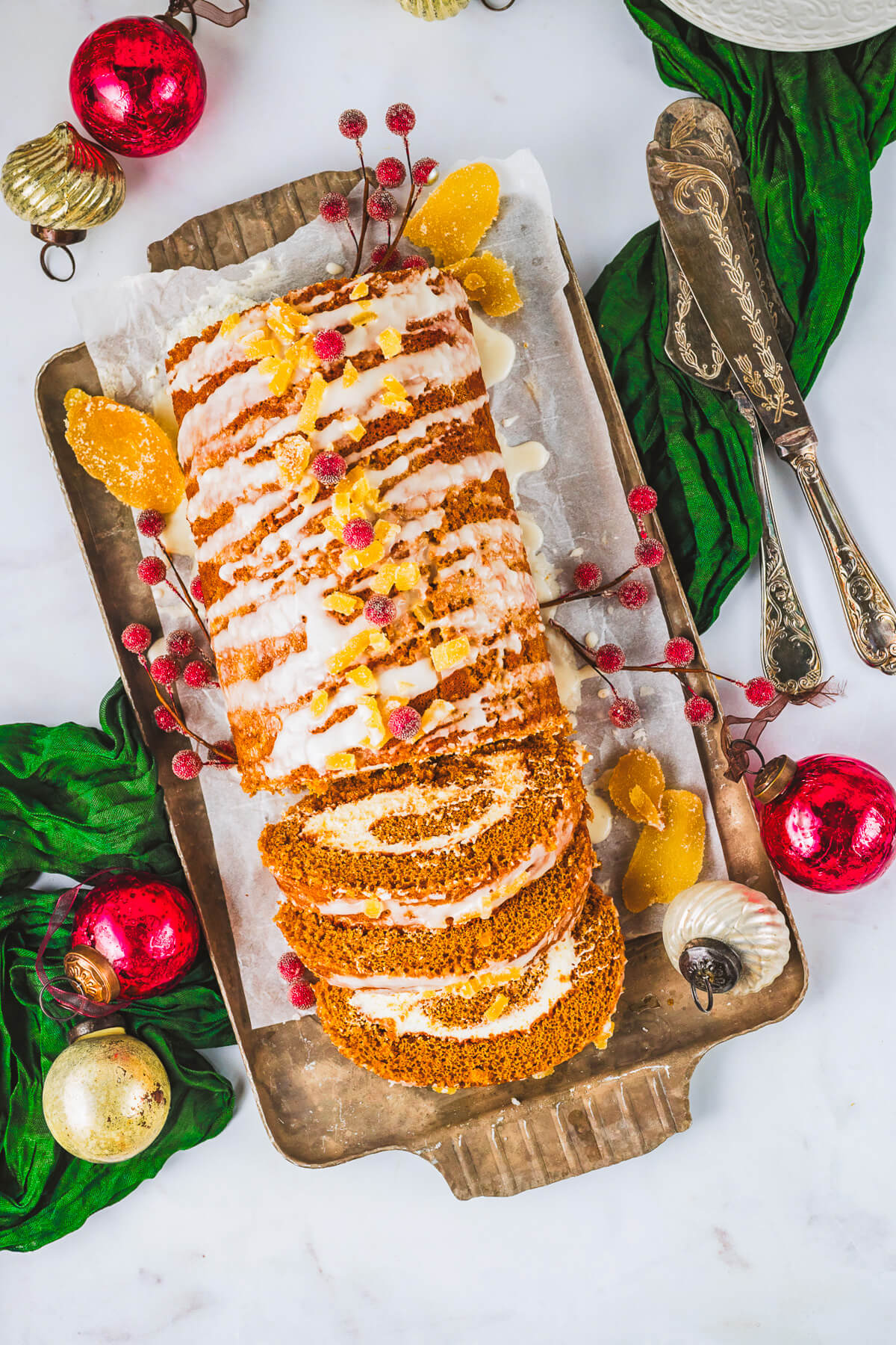 An entire decorated Gingerbread Swiss Roll Cake with slices showing the perfect swirl pattern.