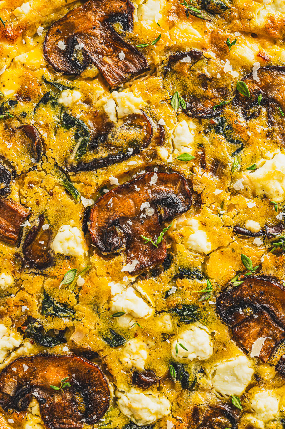 Close up photo showing spinach, mushrooms, goat cheese in a baked egg quiche.