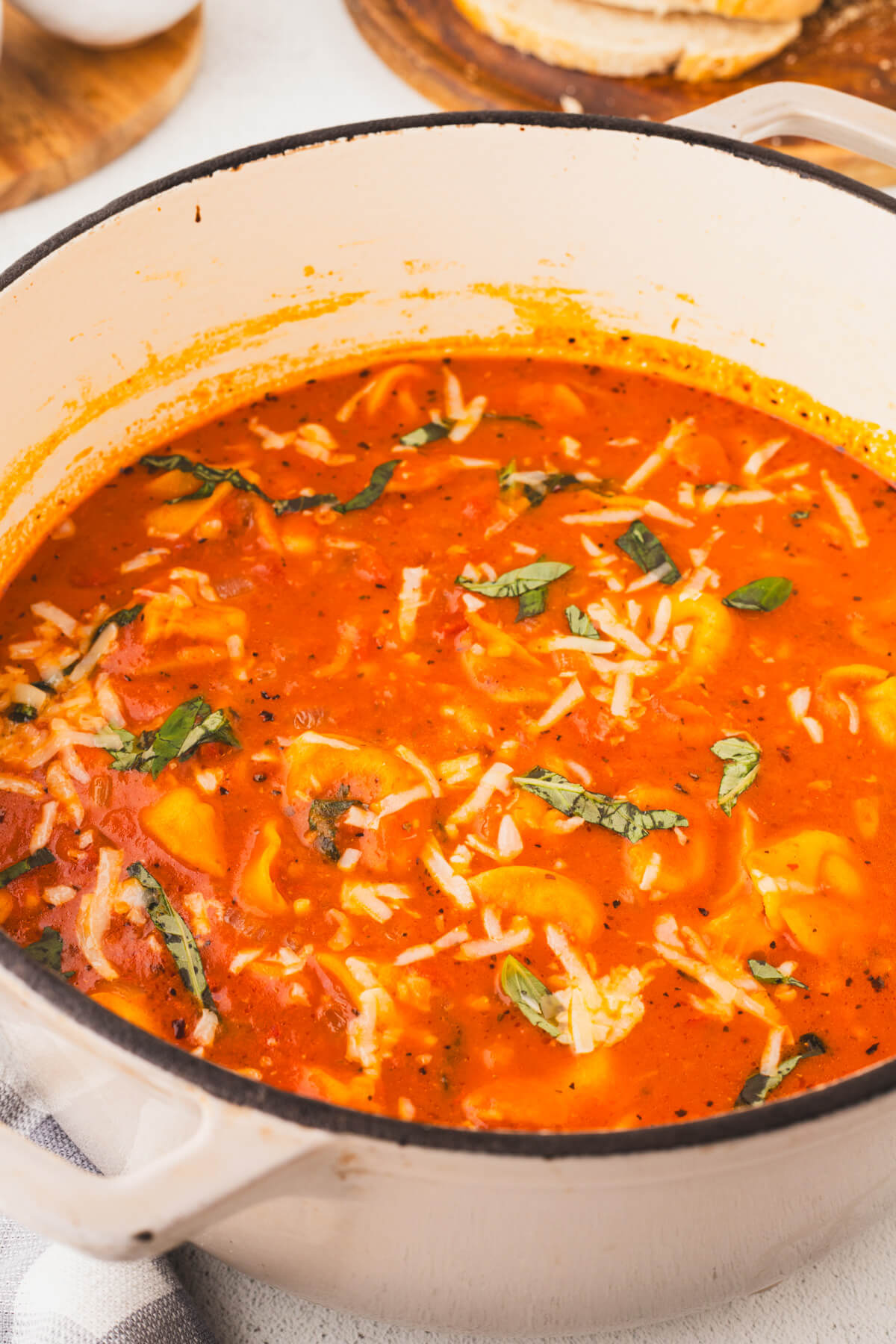 A white Dutch oven filled with creamy cheesy tomato tortellini soup.