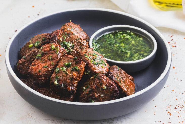 A low bowl full of perfectly seared air fryer steak bites topped with garlic parsley butter.