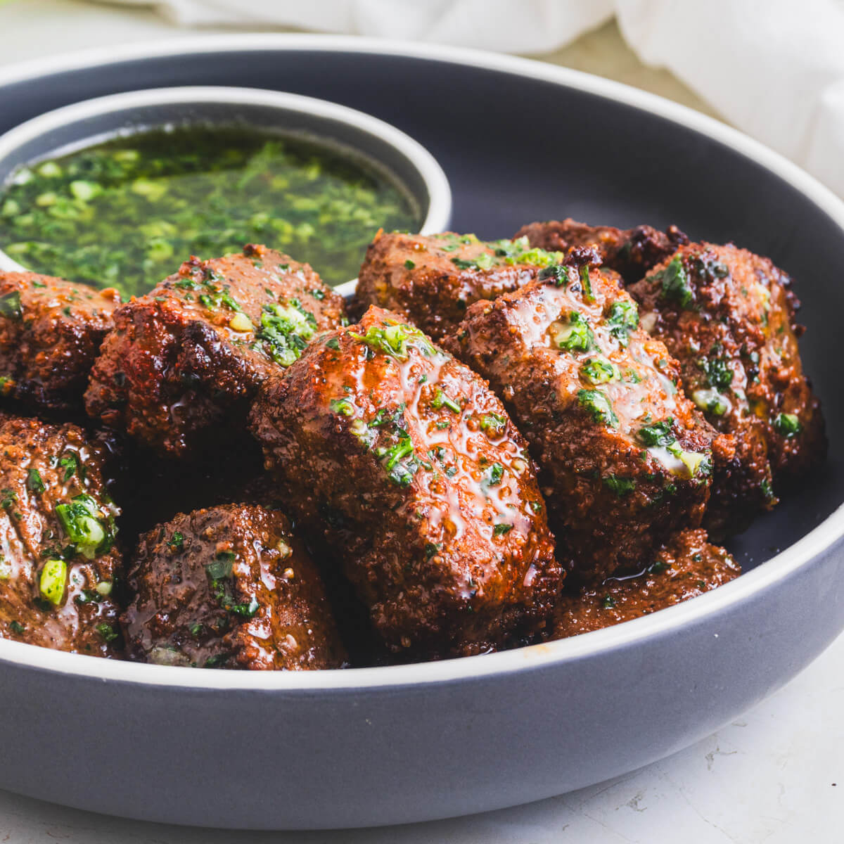 A low bowl full of perfectly seared air fryer steak bites topped with garlic parsley butter.