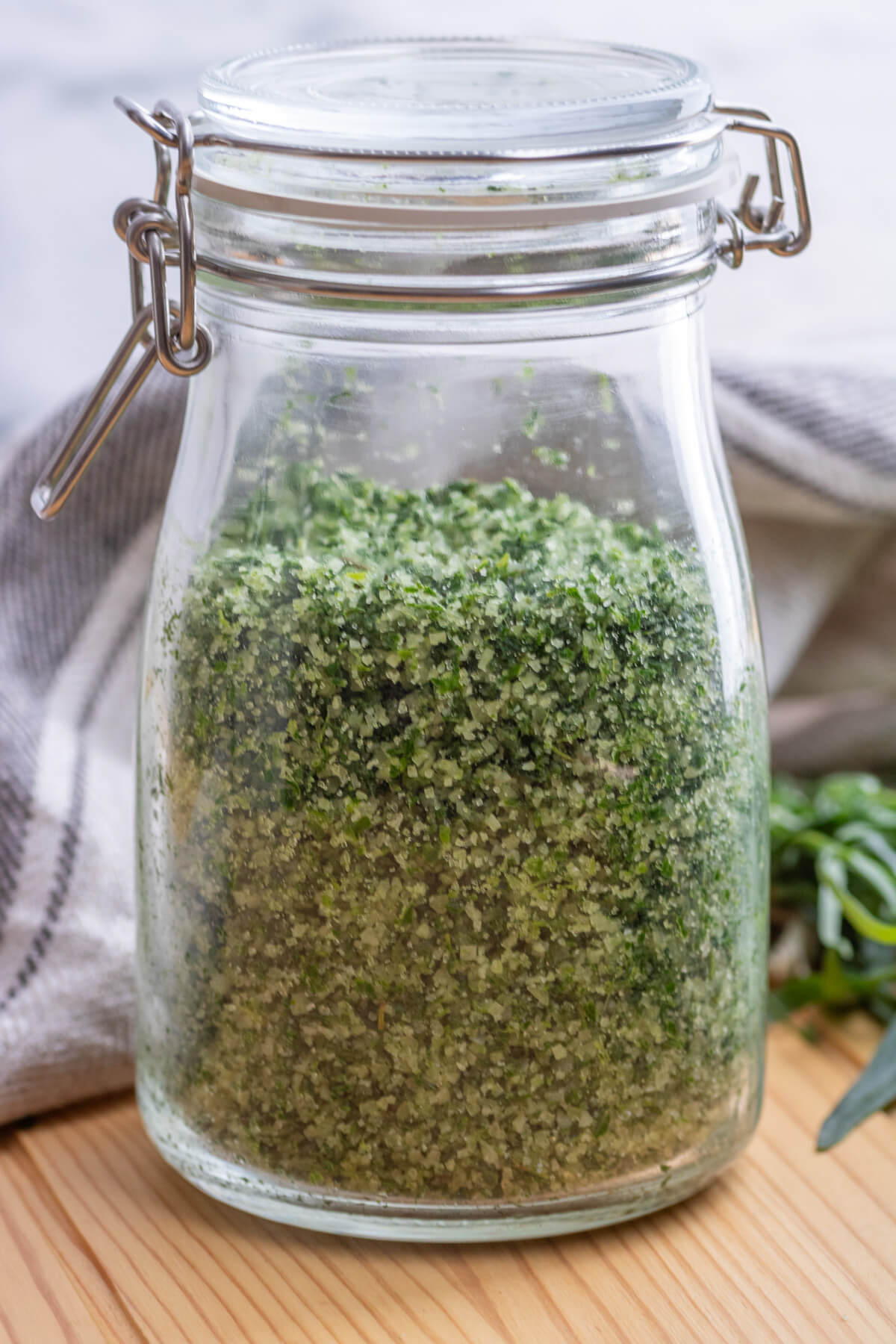 A glass jar with a tight fitting lid containing herb salt.
