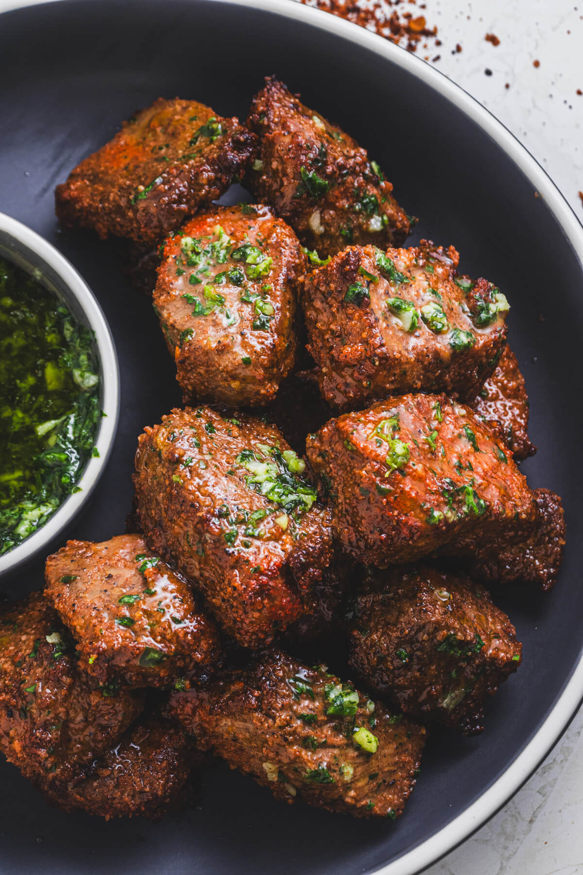 A low bowl full of perfectly seared air fryer steak bites topped with garlic parsley butter.