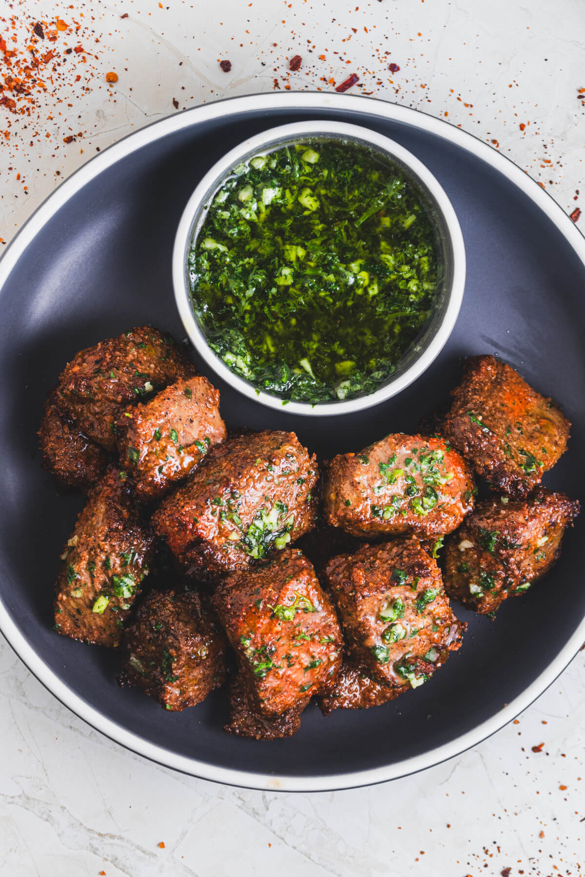 A low bowl full of perfectly seared air fryer steak bites topped with garlic parsley butter.