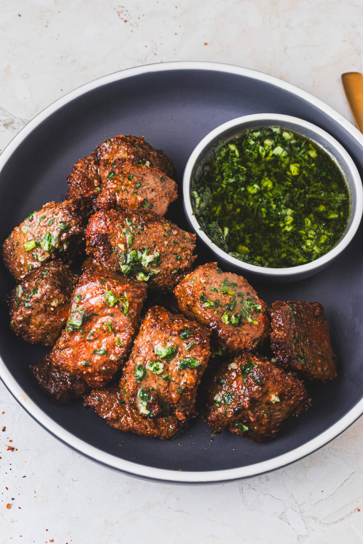 A low bowl full of perfectly seared air fryer steak bites topped with garlic parsley butter.