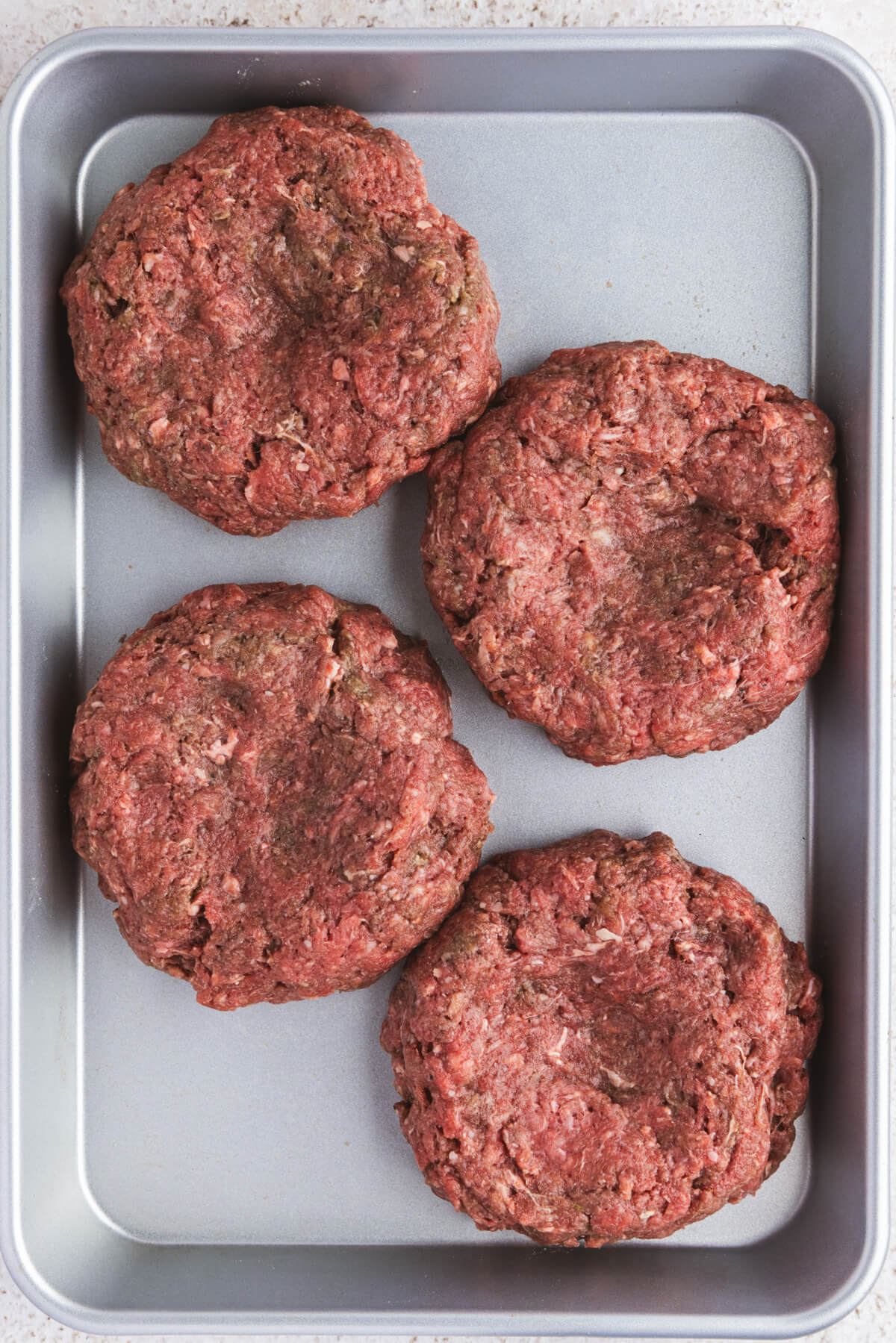 A tray of raw bison burger patties.