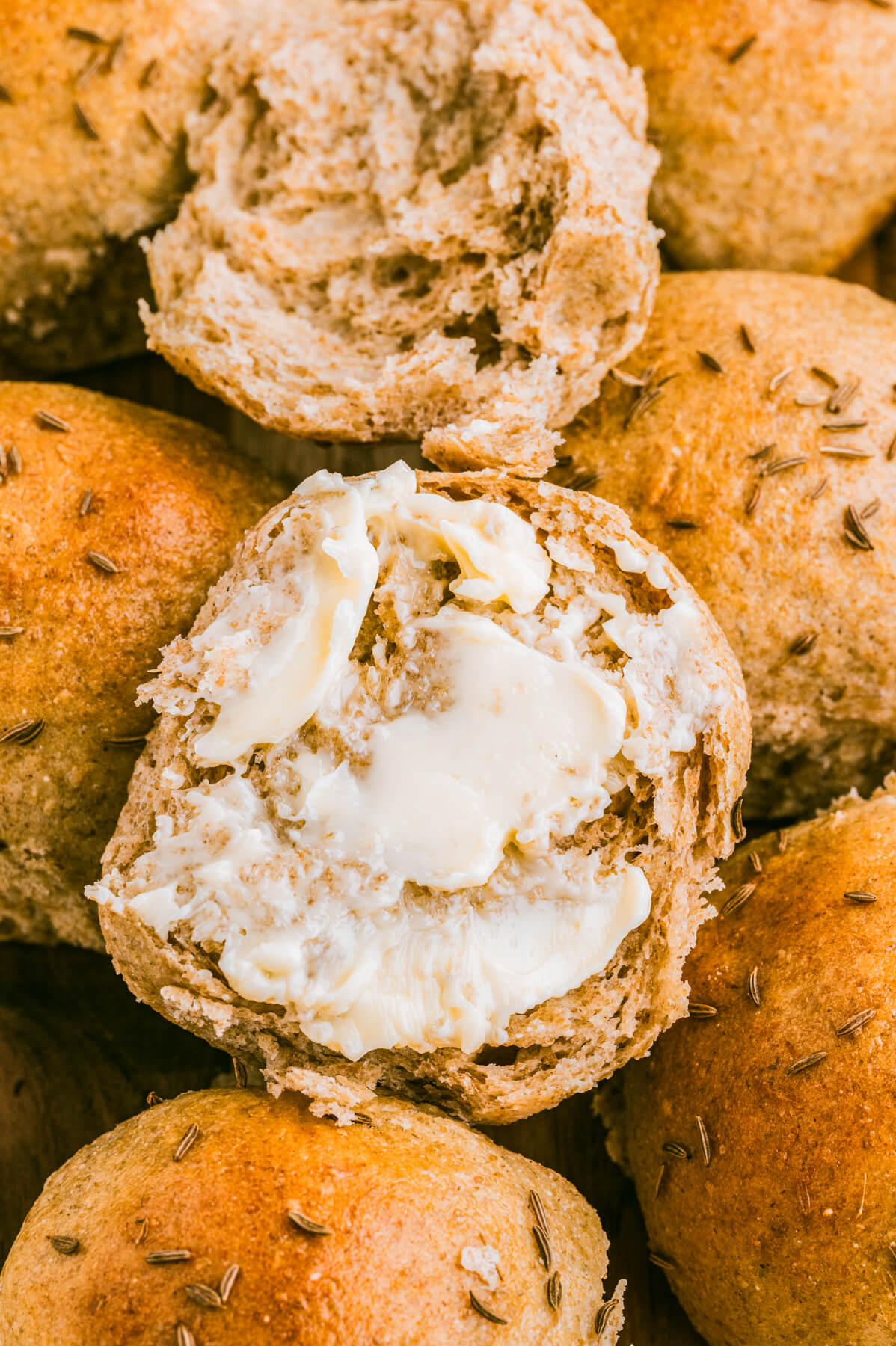 A butter spread on an open rye dinner roll.