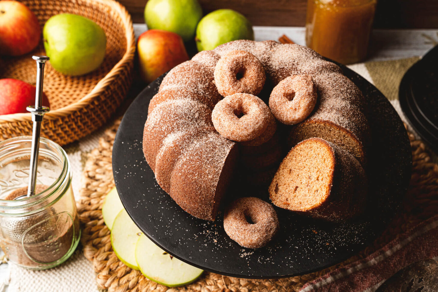 A beautiful brown Apple Cider Donut Cake with slices missing and mini donuts filling the middle hole.