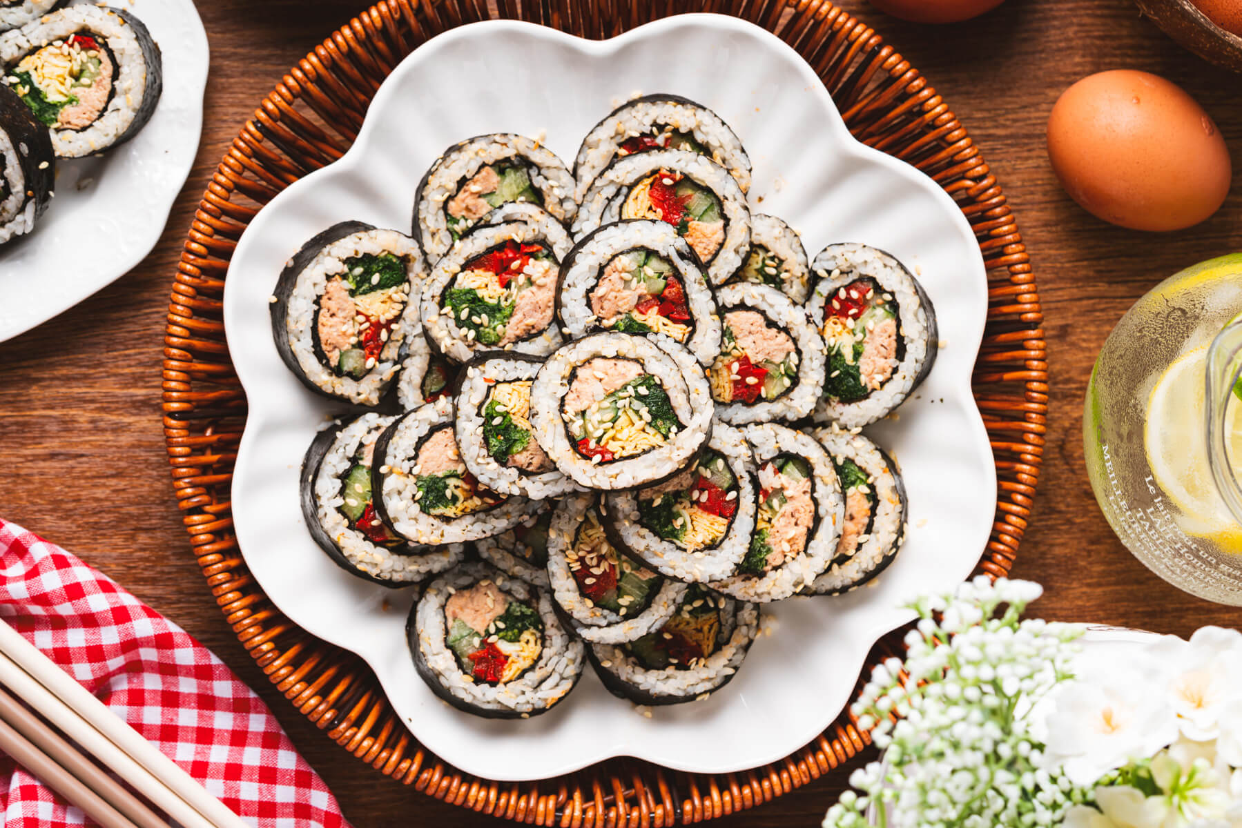 A plate of Tuna Kimbap rolls featuring canned tuna in mayonnaise, egg omelet, spinach, and red bell pepper wrapped in seaweed and rice.