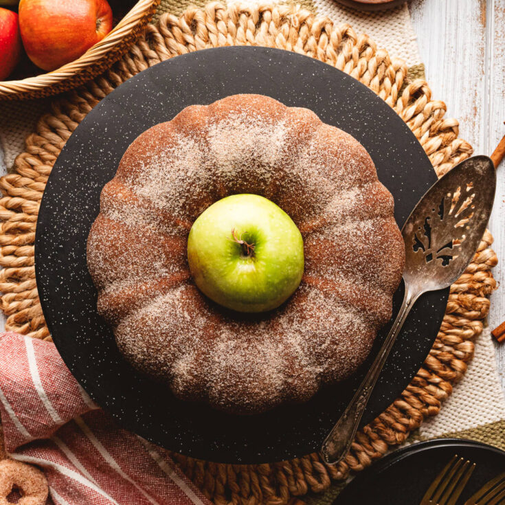 A beautiful brown Apple Cider Donut Cake with an apple in the centre.