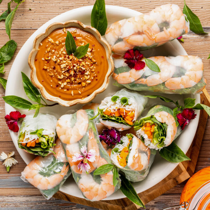 A platter of vibrant Vietnamese Shrimp Salad rolls sliced in half showing bright vegetables and noodles.