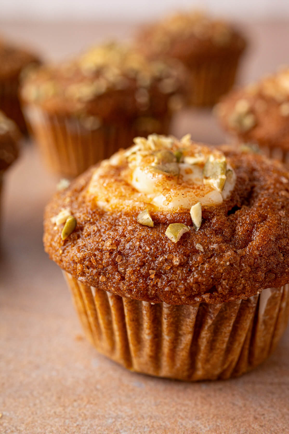 A group of golden baked Pumpkin Cream Cheese Muffins with a cream cheese, sugar, and pumpkin seed topping.