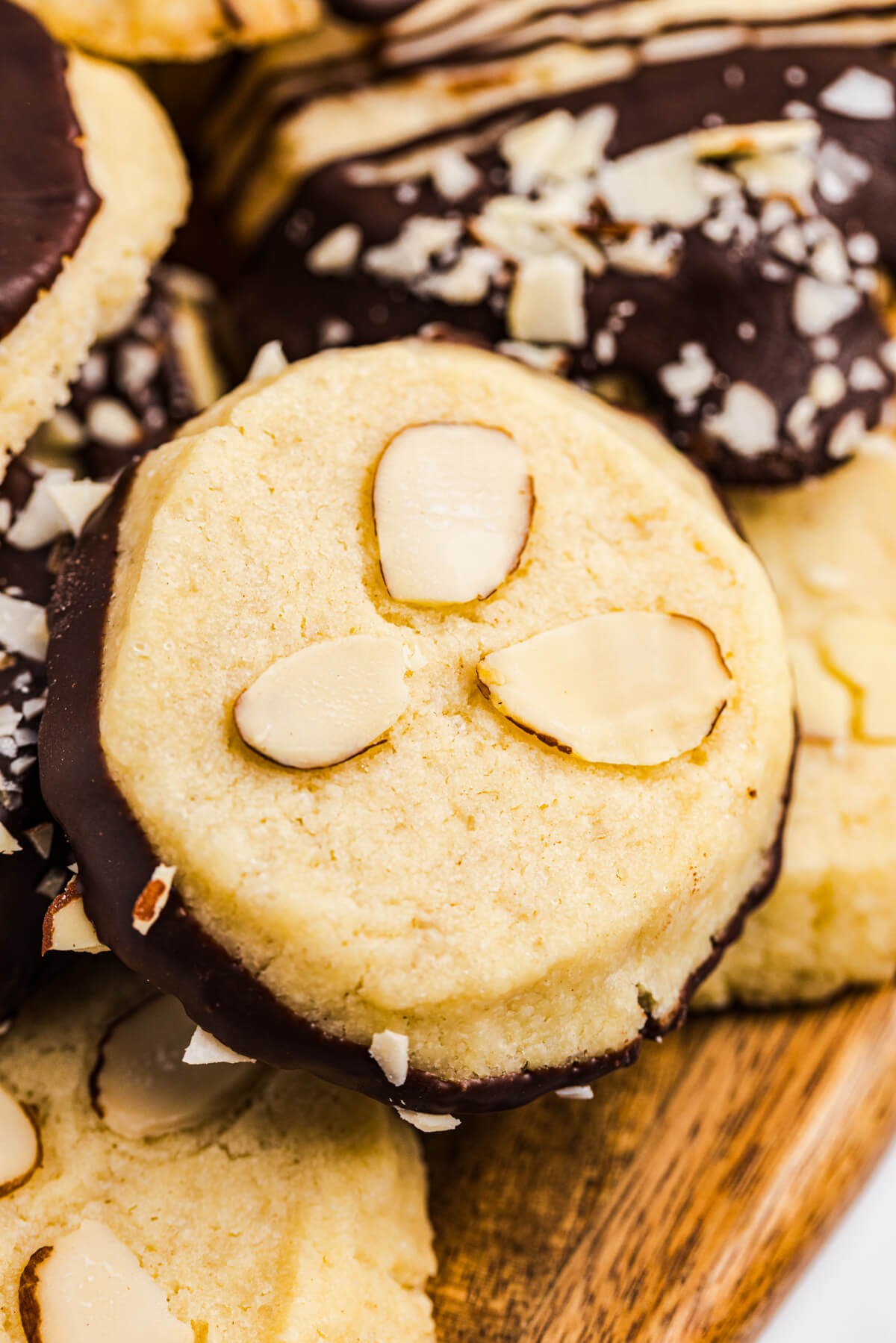 One round shortbread cookie topped with three sliced almonds on top of a pile of decorated cookies.