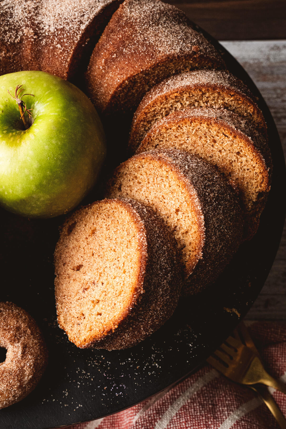 Slices of apple cider donut cake surrounding a green apple.