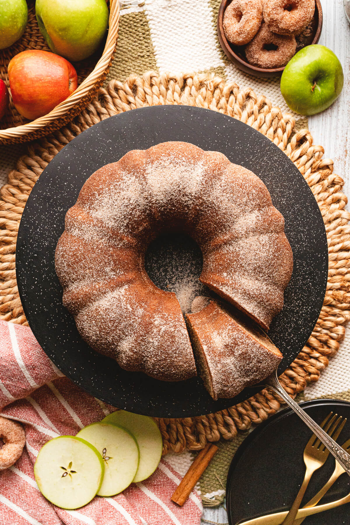 A beautiful brown Apple Cider Donut Cake with a slice missing.