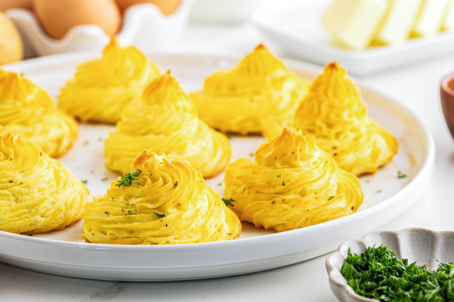 Golden baked swirls of rich baked Pommes Duchess on a white plate.