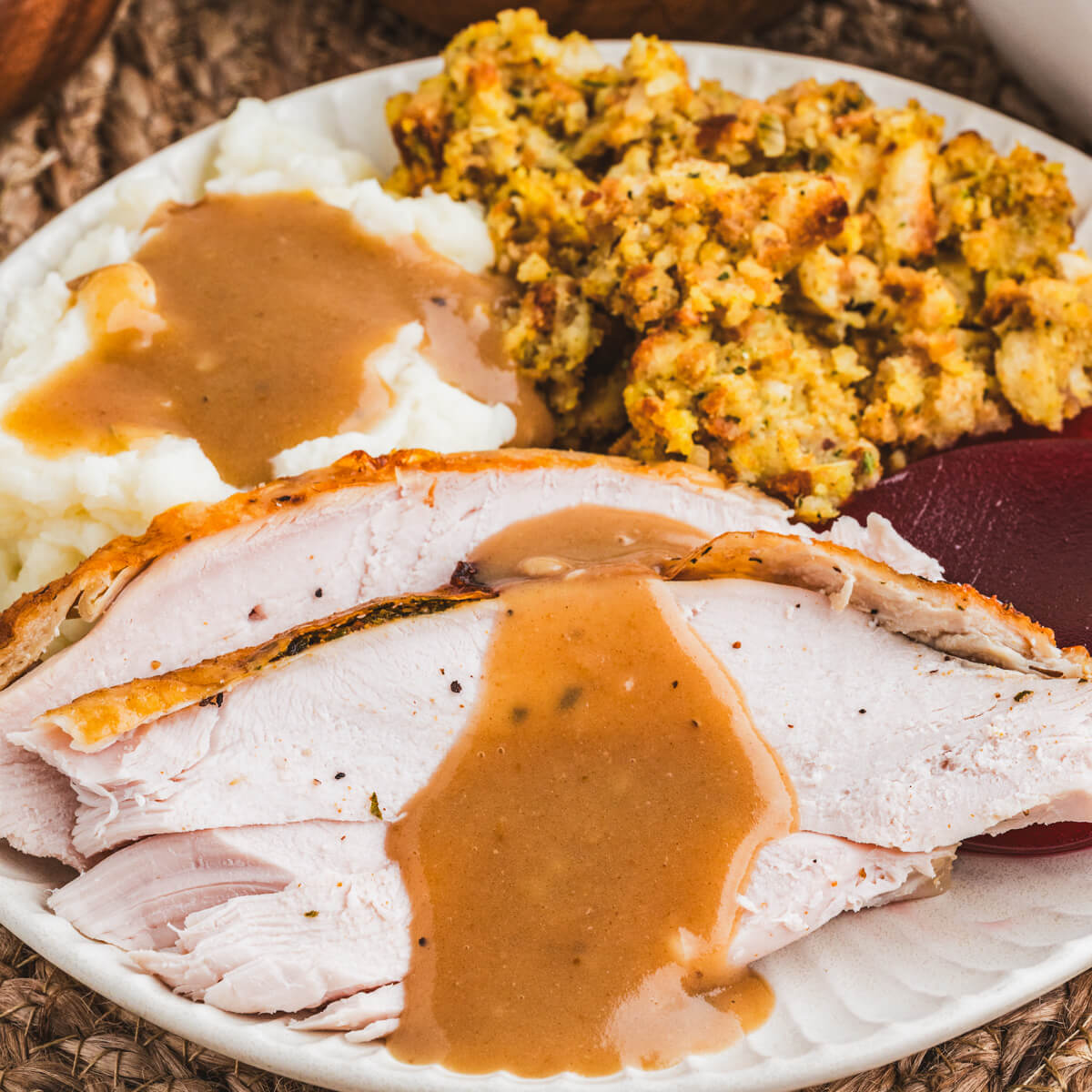 Sliced of slow cooker turkey breast covered in turkey gravy on a dinner plate.