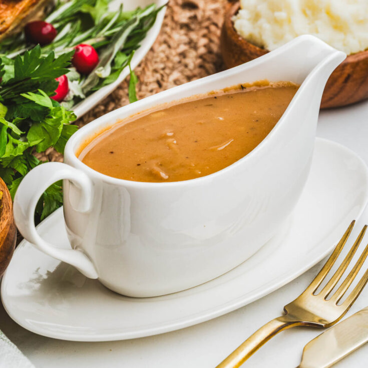 A white gravy boat filled with rich brown gravy.
