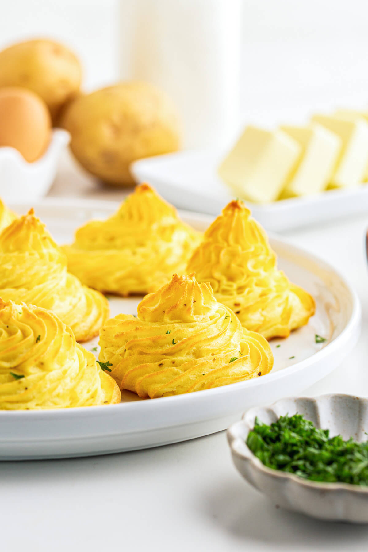 Golden baked swirls of rich baked Pommes Duchess on a white plate.