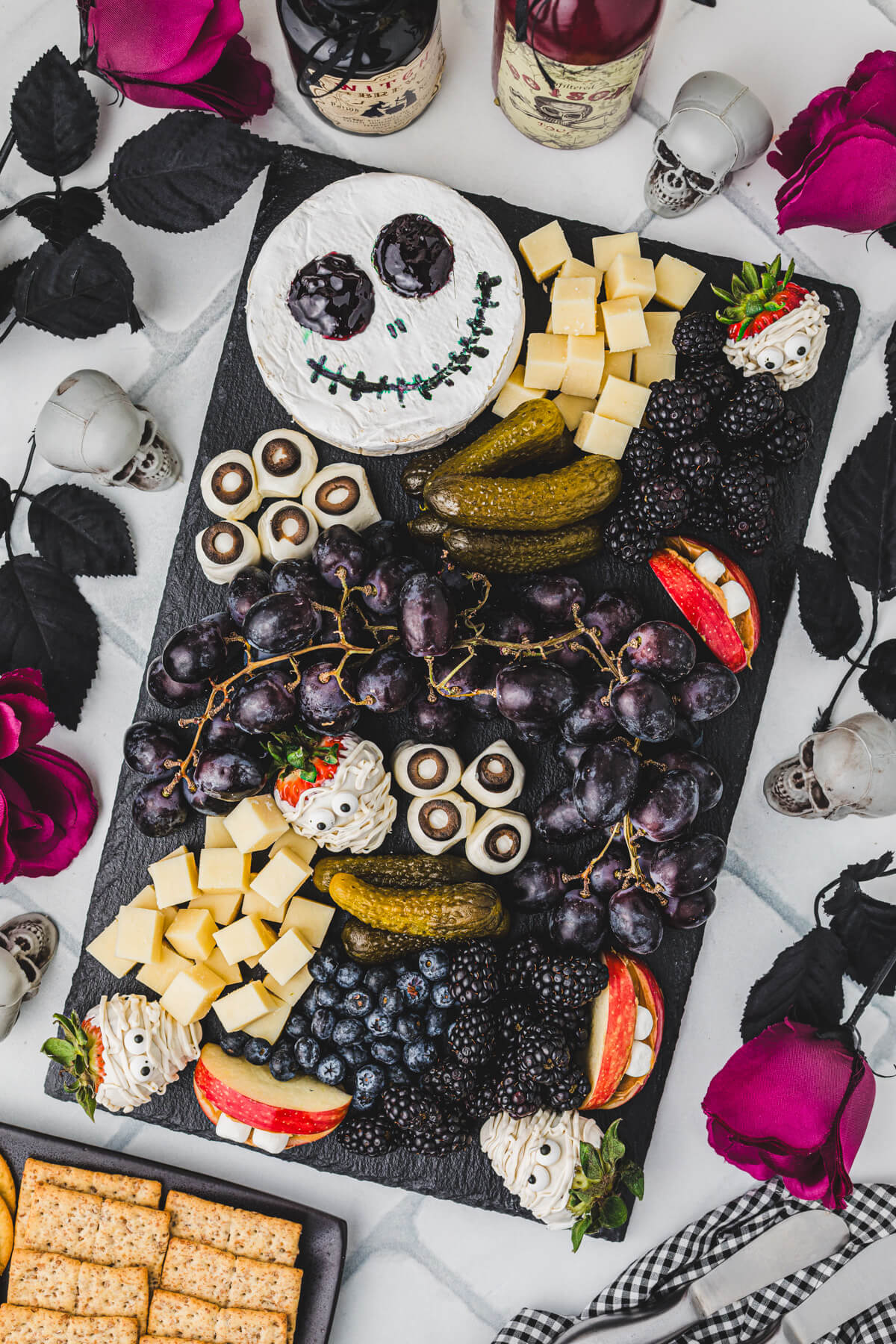 A Halloween party table containing a large charcuterie board featuring great ideas for spooky snacks.