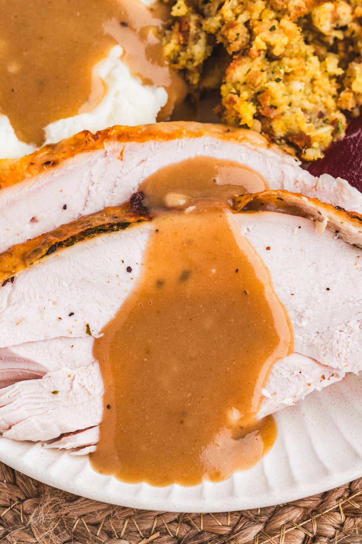 Slices of roast turkey covered in rich brown turkey gravy.