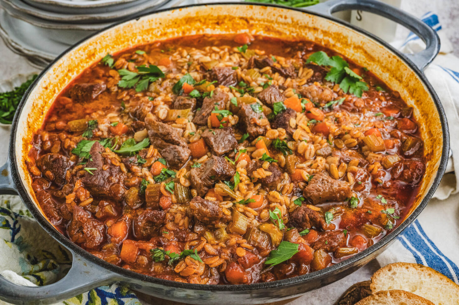 A large pot filled with hearty beef chunks, barley, vegetables in a luxurious broth.