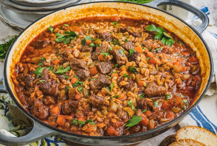 A large pot filled with hearty beef chunks, barley, vegetables in a luxurious broth.