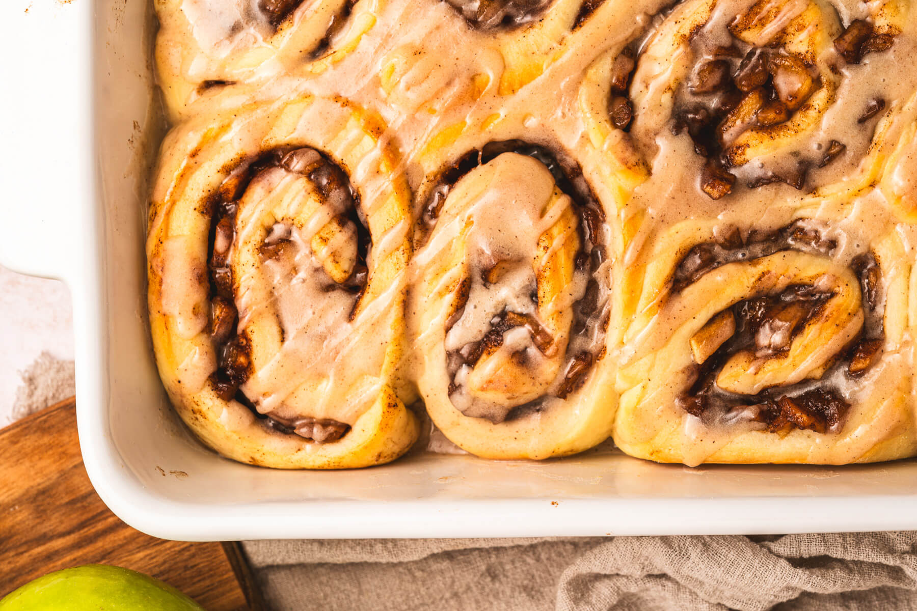 A white baking dish containing freshly baked apple pie cinnamon rolls.