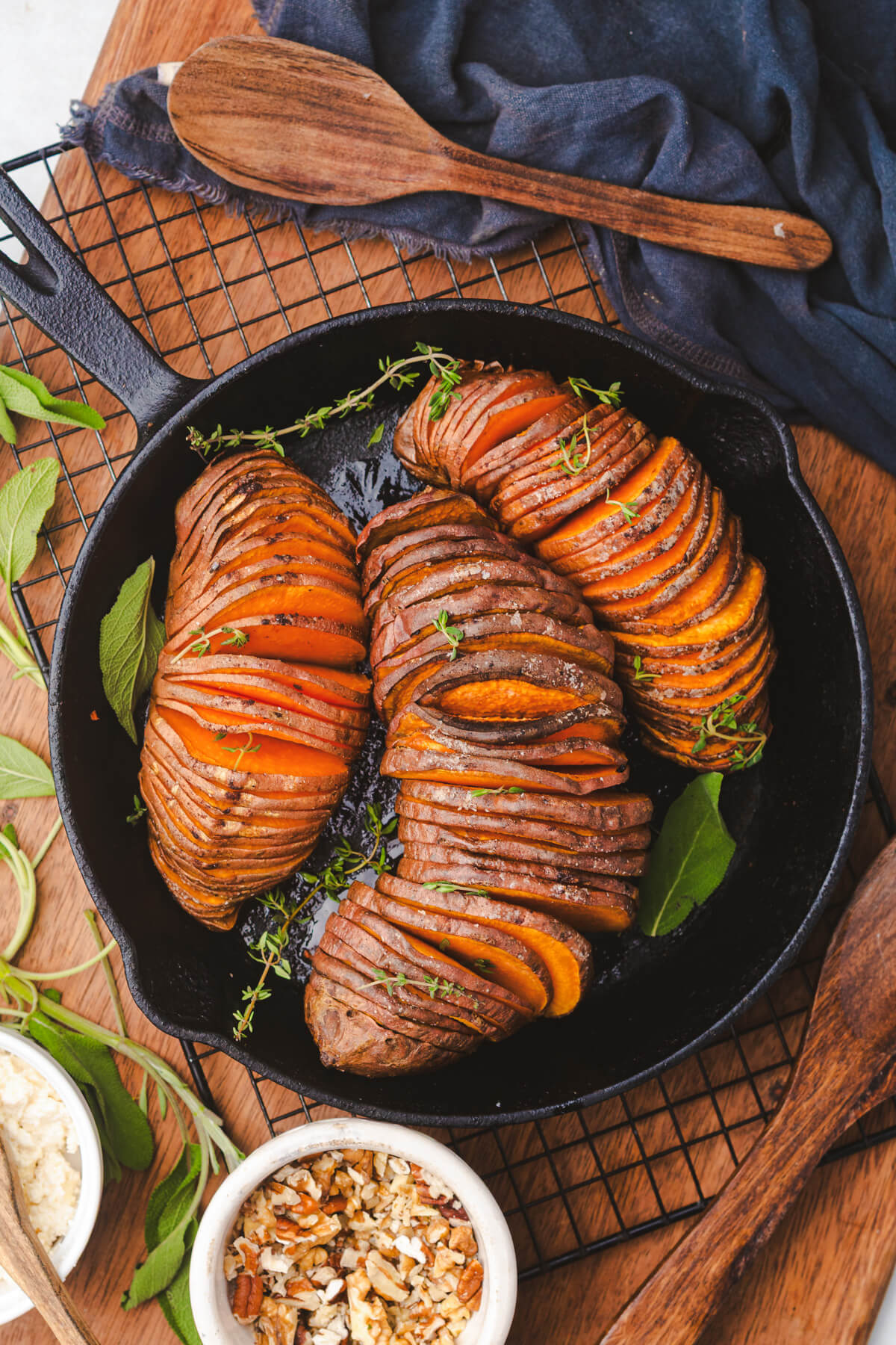 Three perfectly roasted vibrant orange hasselback sweet potatoes in a cast iron pan.