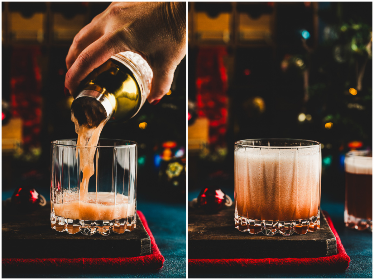 A person pours a sour amaretto cherry cocktail into a rocks cocktail glass.