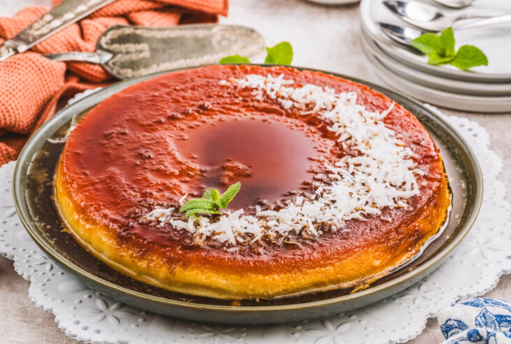 A whole coconut flan topped with a golden brown caramel and coconut flakes.