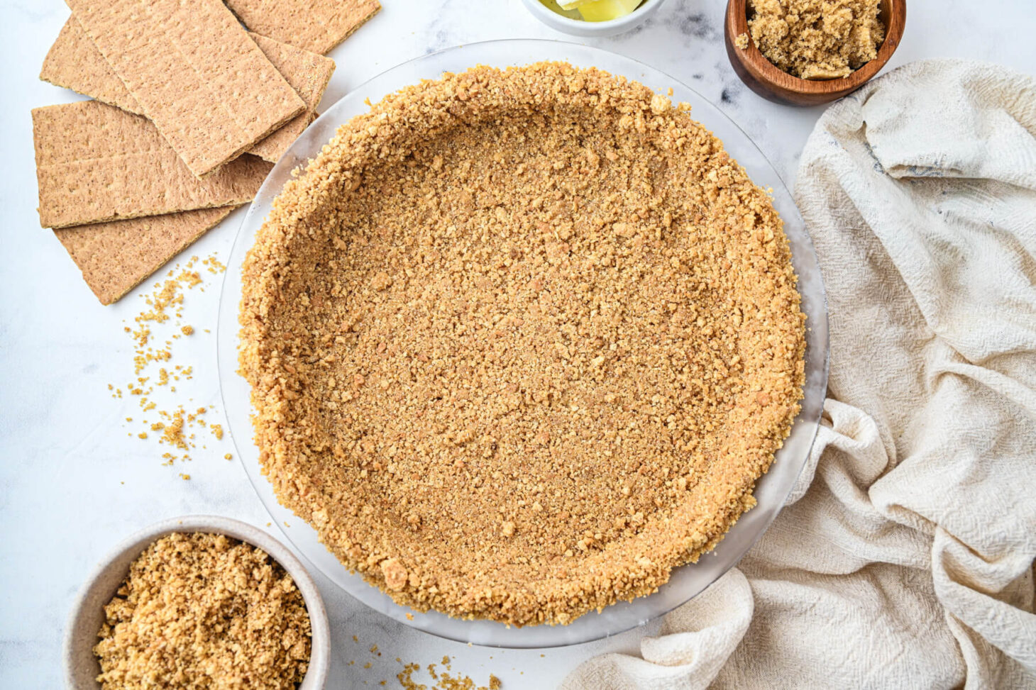 An unfilled 9 inch graham cracker pie crust surrounded by baking ingredients.