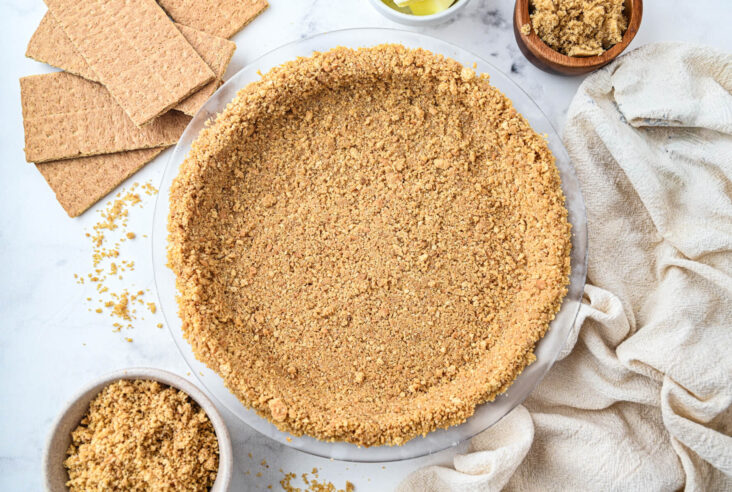 An unfilled 9 inch graham cracker pie crust surrounded by baking ingredients.