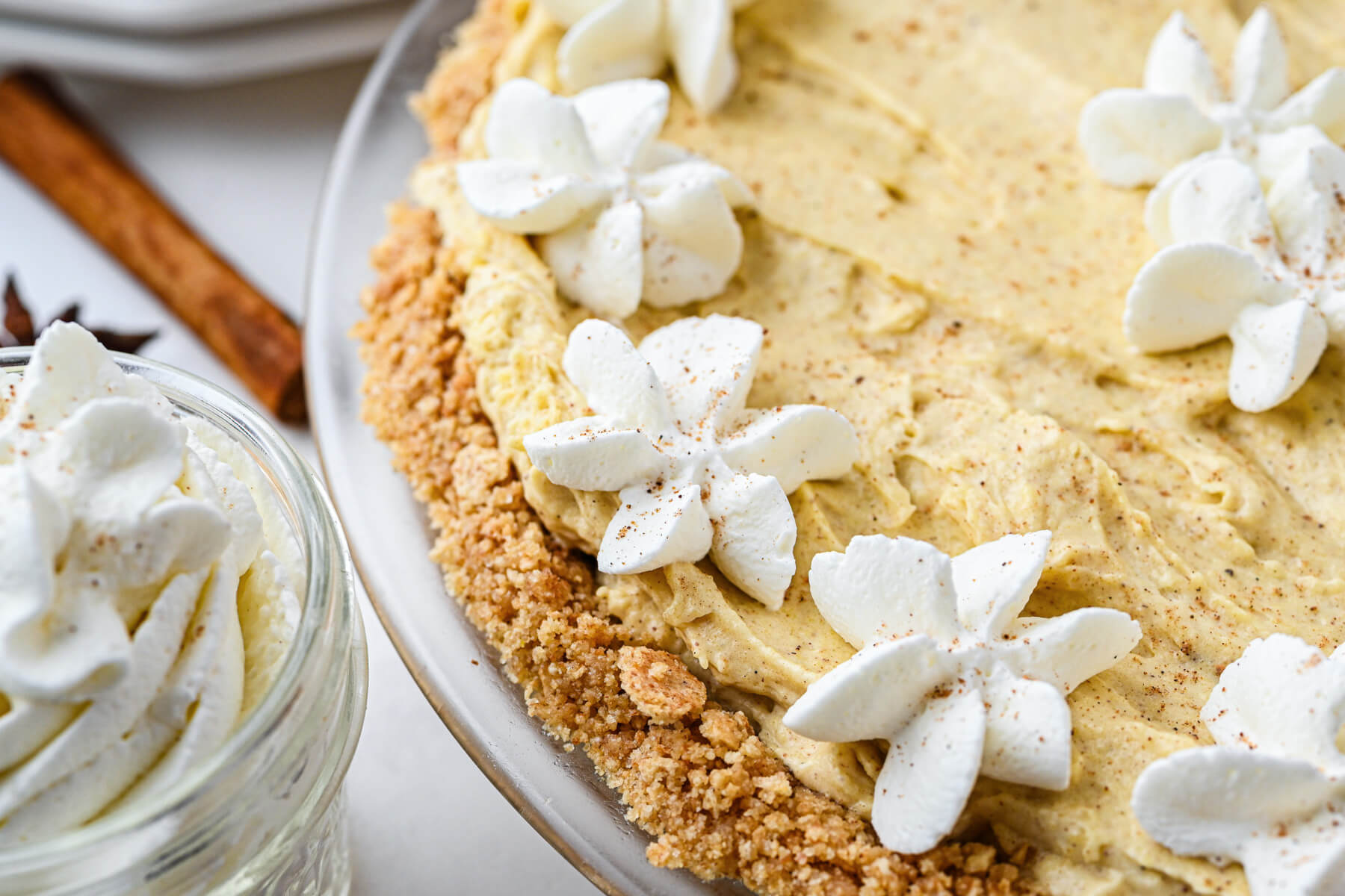 Close photo of a no bake eggnog pie decorated with whipped cream stars and freshly grated nutmeg.