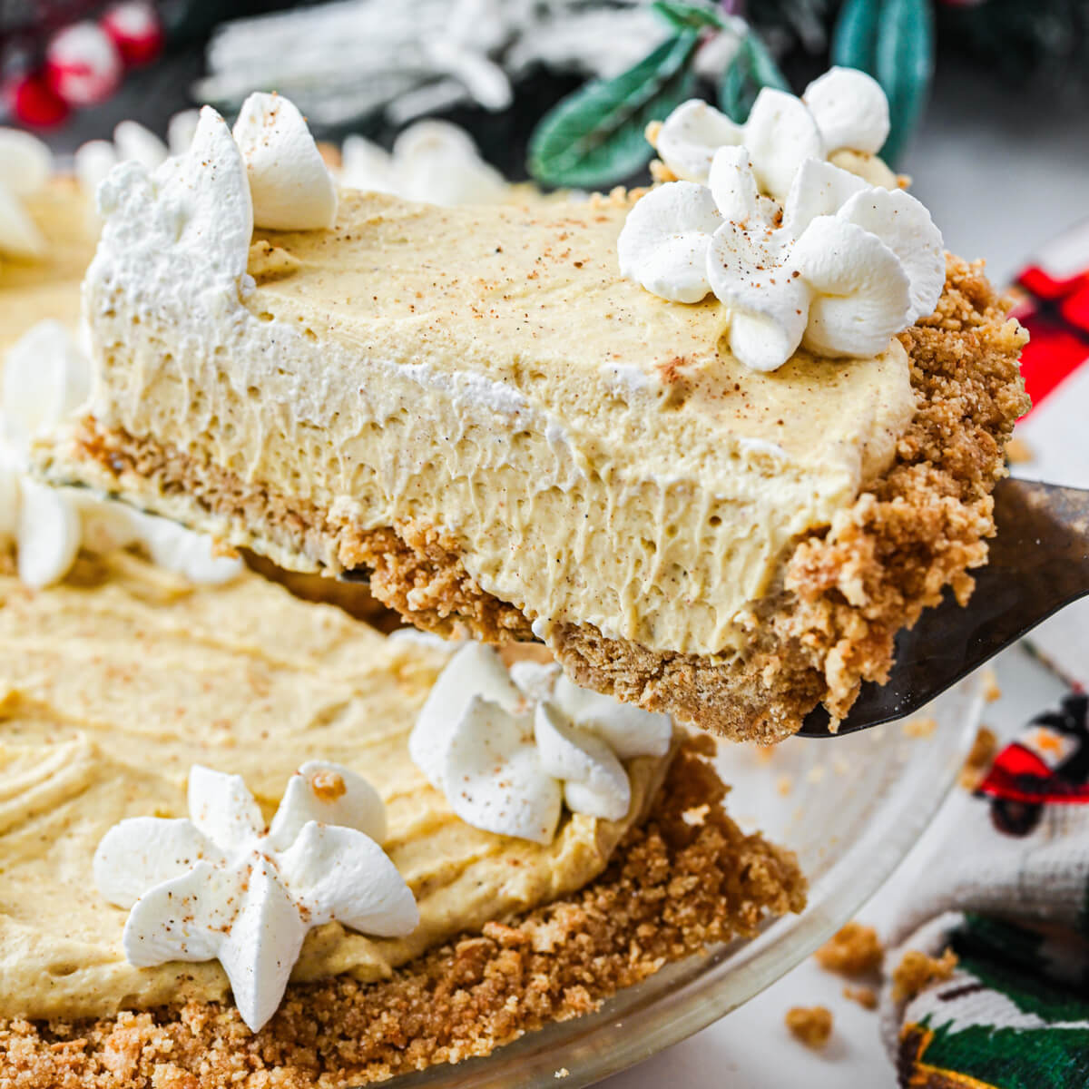A pie server holds up a slice of no bake eggnog pie over the remaining pie.