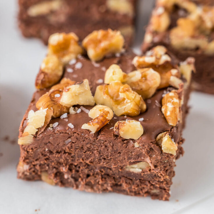A chocolate walnut fudge square topped with chopped walnuts and sea salt.
