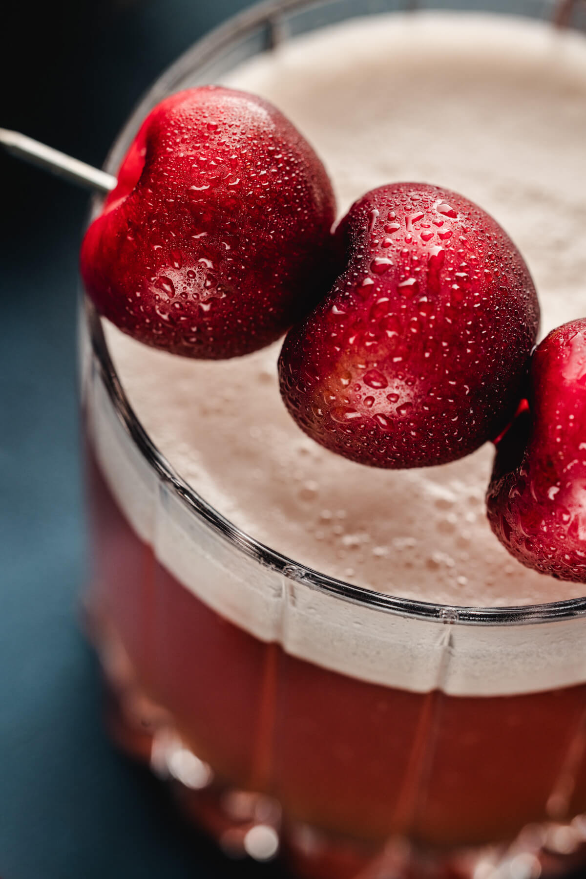 Close up of cherry garnish on top of a cherry amaretto sour cocktail.