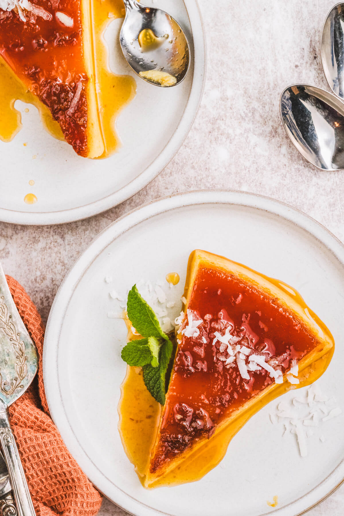 Two slices of creamy coconut flan topped with a golden brown caramel and coconut flakes.