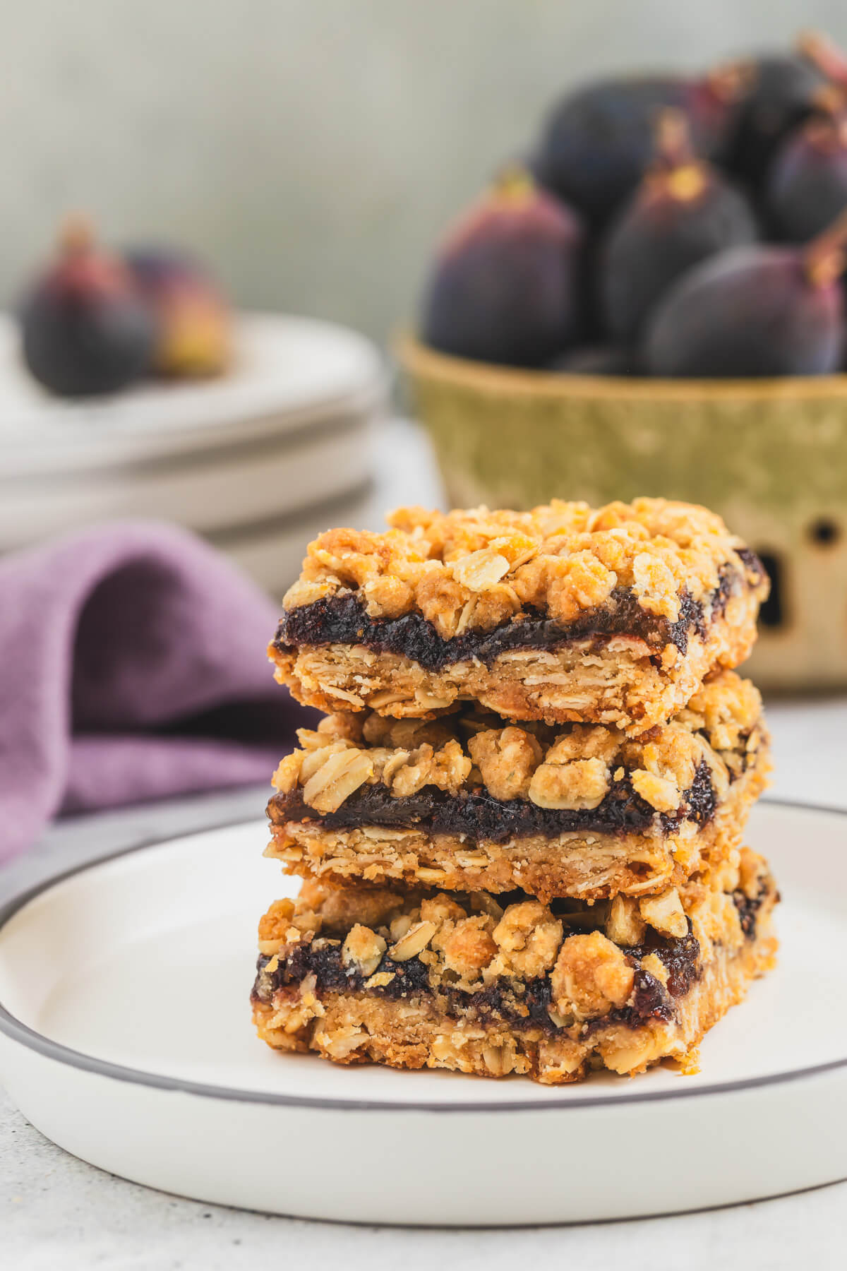 A stack of golden baked crumby Fig Bars on a white plate.