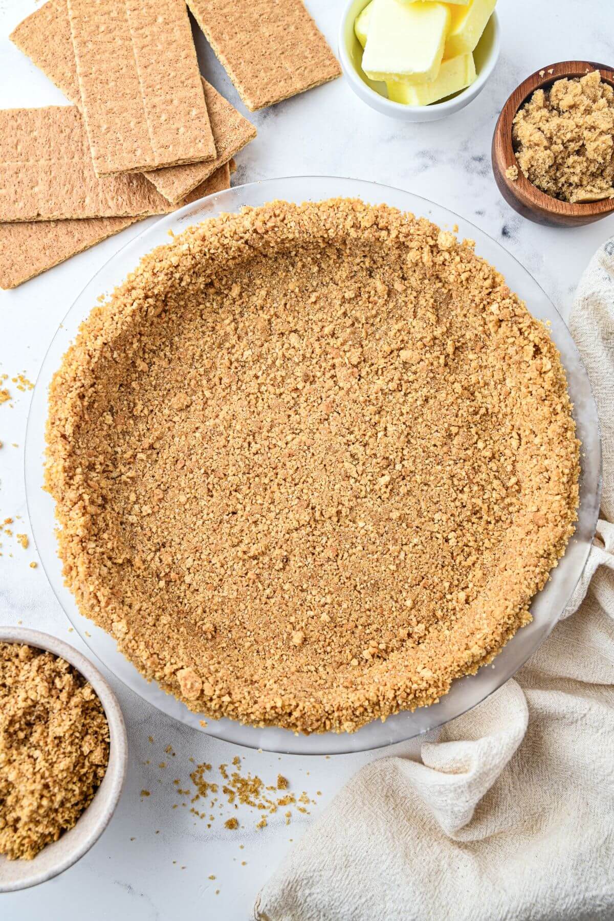 An unfilled 9 inch graham cracker pie crust surrounded by baking ingredients.
