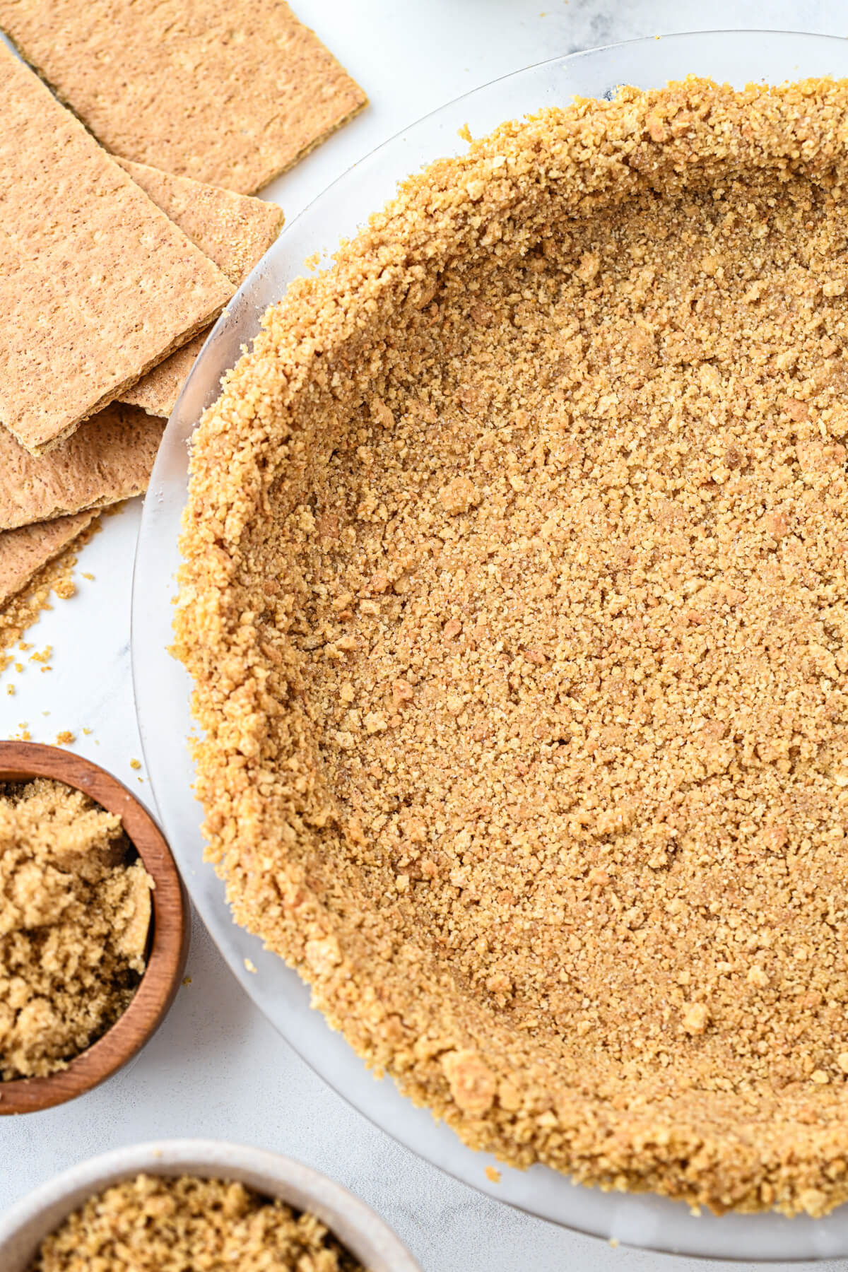 An unfilled 9 inch graham cracker pie crust surrounded by baking ingredients.