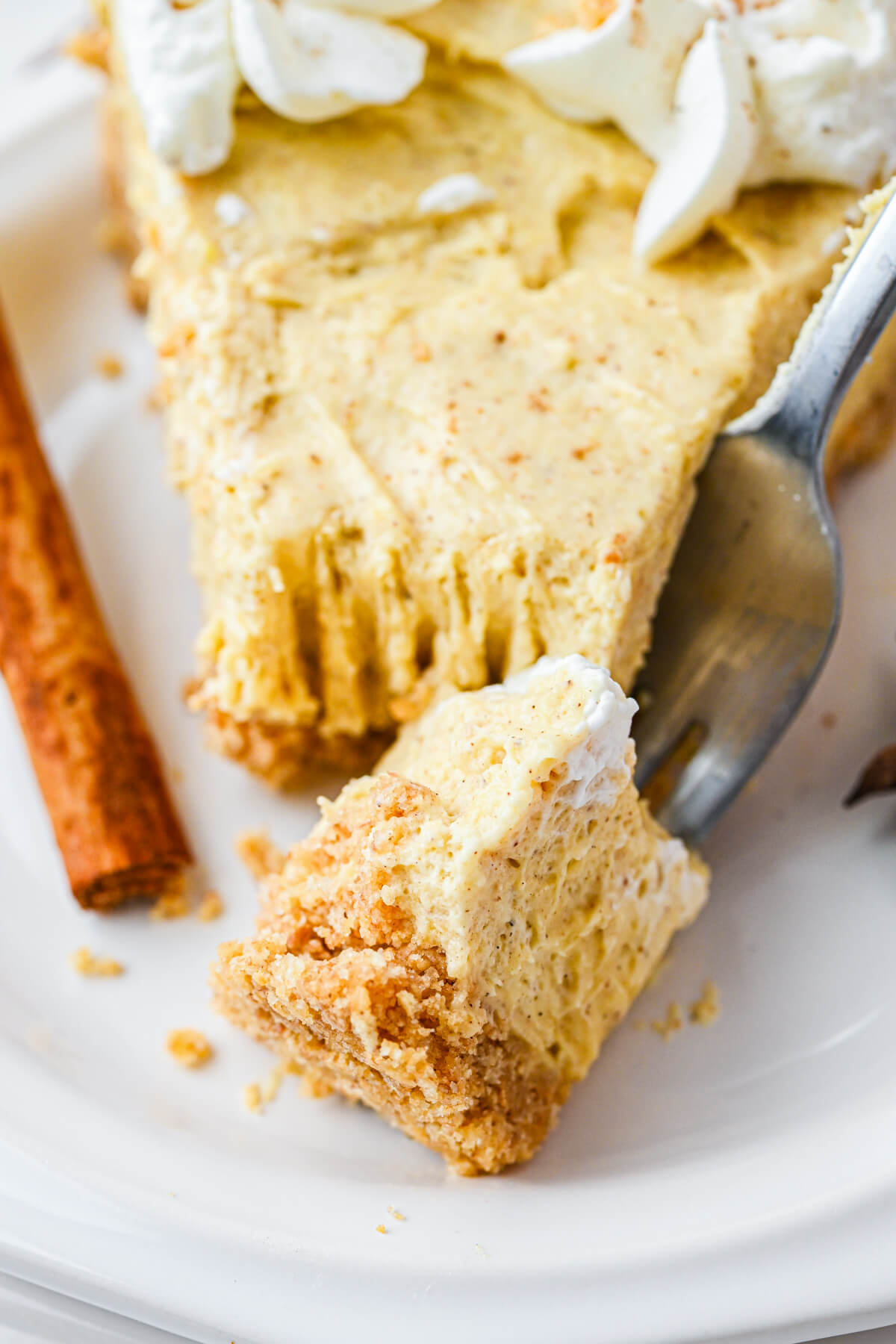 A forkful of eggnog pie sits on a white plate alongside the rest of the pie slice.
