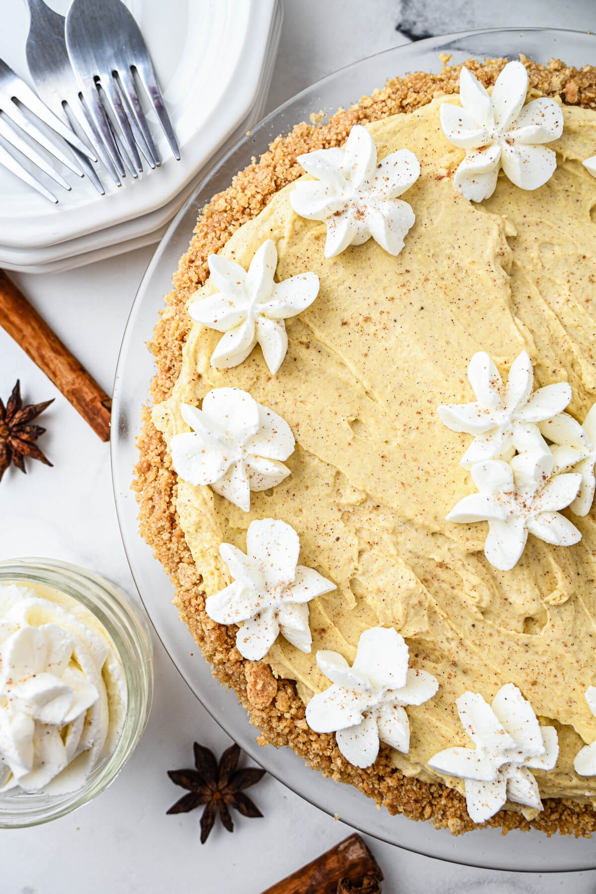 Half of a no bake eggnog pie decorated with whipped cream stars on a holiday dinner table.