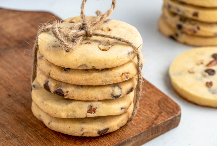 A stack of golden baked shortbread cookies studded with chocolate chips and pecans.