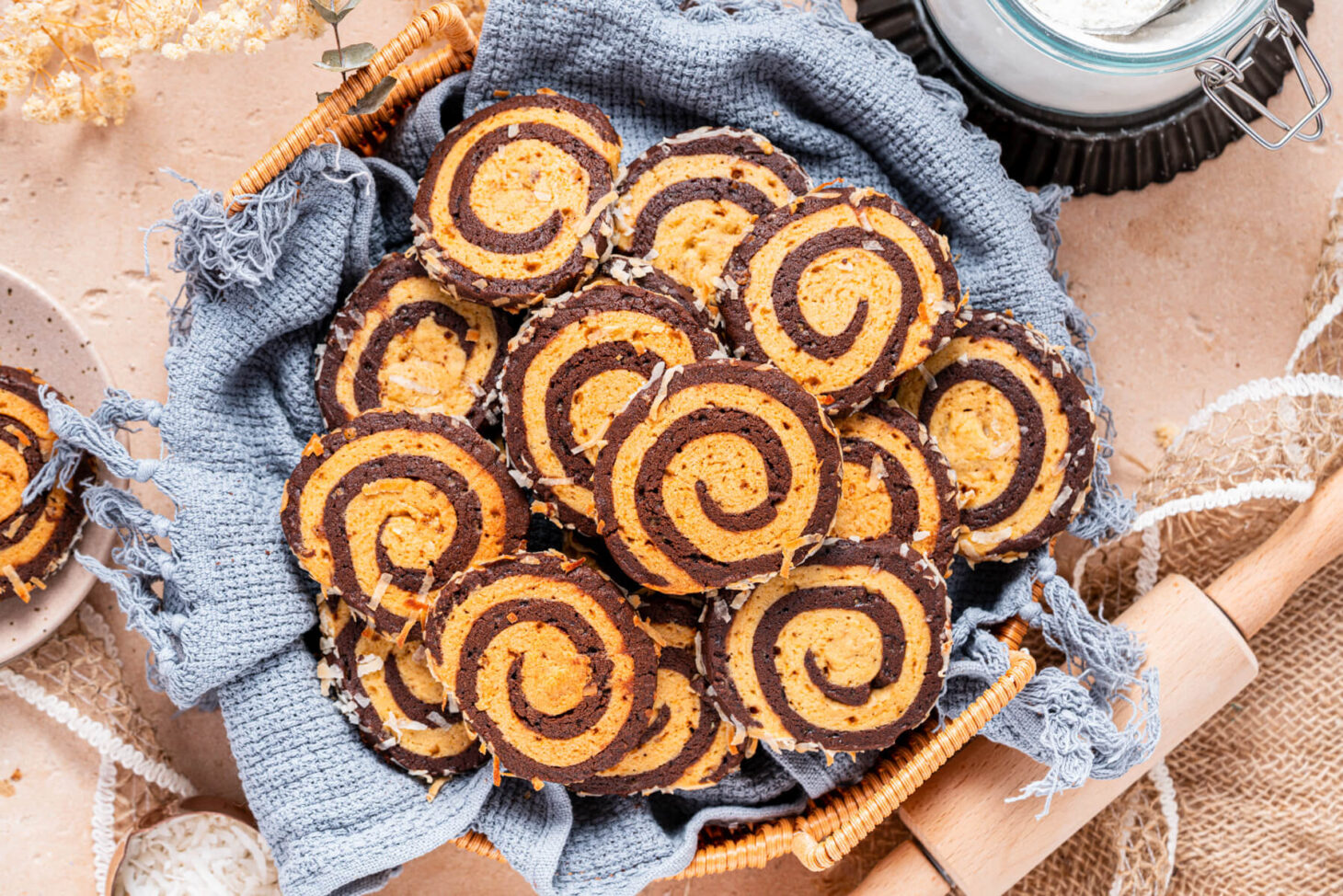 A plate of Chocolate and Vanilla Pinwheel Cookies on a baking counter.