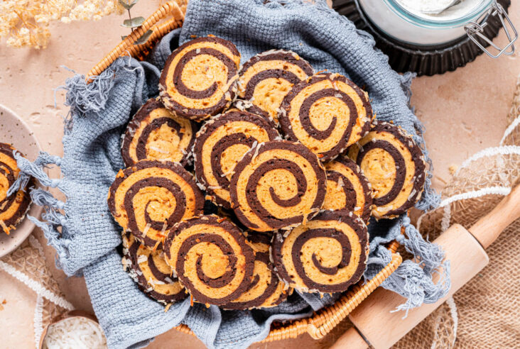 A plate of Chocolate and Vanilla Pinwheel Cookies on a baking counter.