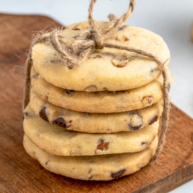 A stack of golden baked shortbread cookies studded with chocolate chips and pecans.