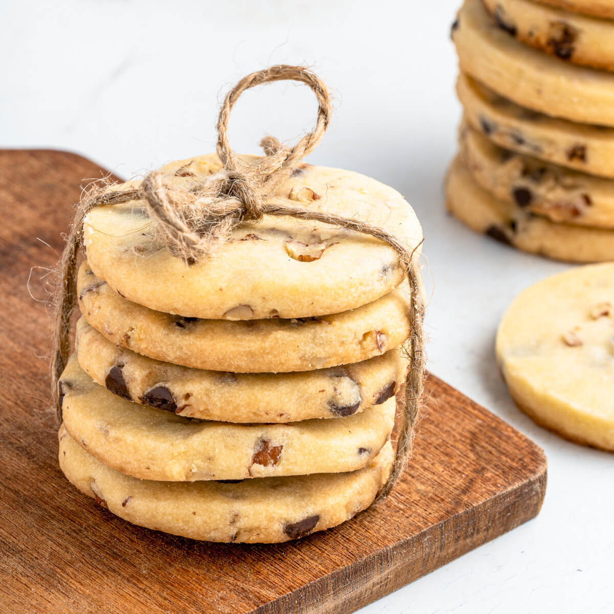 Stacks of golden baked shortbread cookies studded with chocolate chips and pecans.
