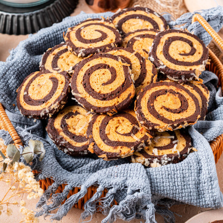 A plate of Chocolate and Vanilla Pinwheel Cookies on a baking counter.